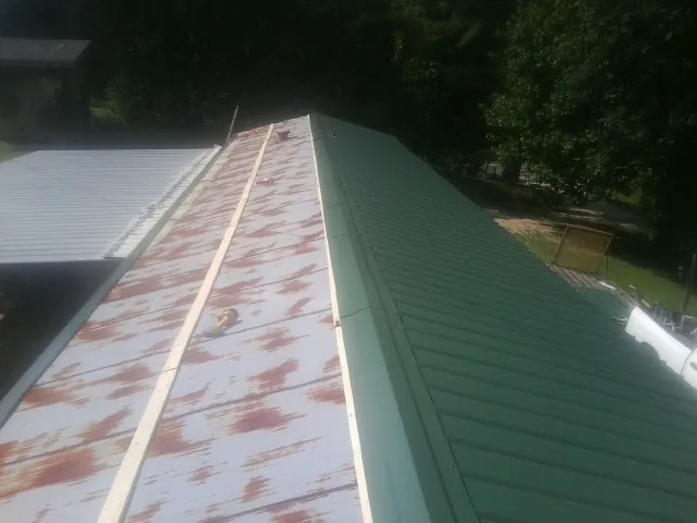 Old rusted panels beside newly installed green metal roofing — Wind Damage Roof Repair by Roofing Brothers in White Stone