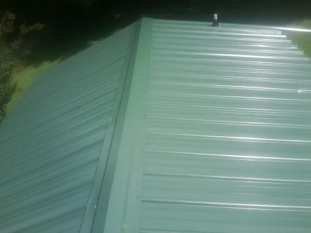 New green metal panels meeting at the ridge of a roof — Flat Roof Repair work by our crew in White Stone
