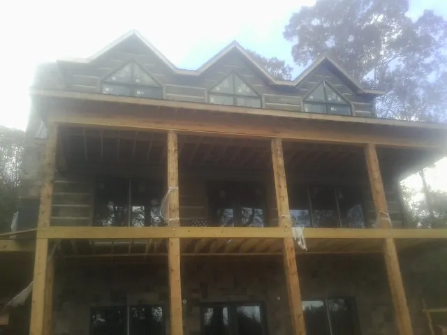 Dormers and porch framing on a large log home under construction — Roof Coating work by our crew in White Stone