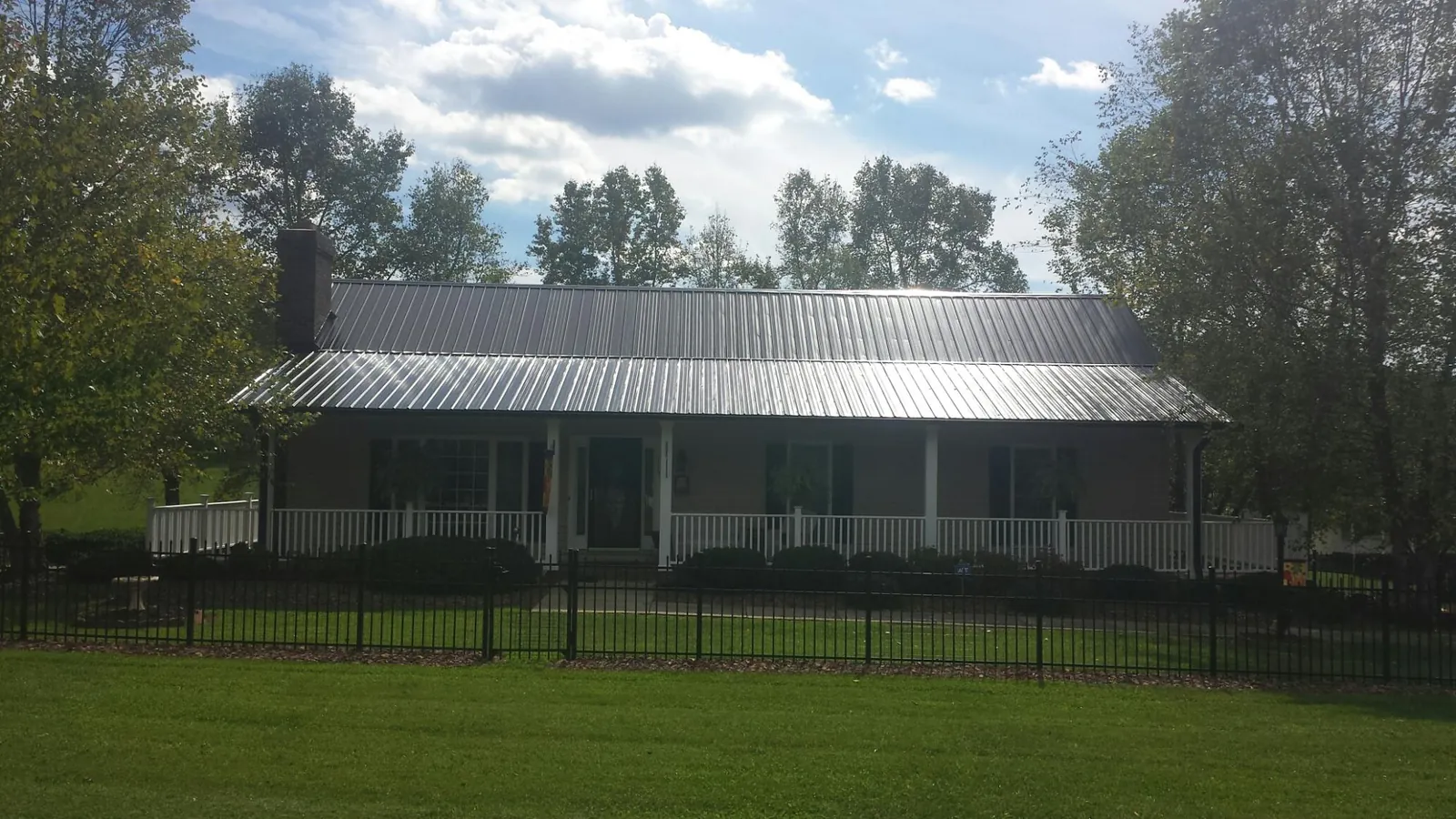 Gray metal roof on a brick ranch with a full width front porch — Gutter Guard Installation work by our crew in White Stone